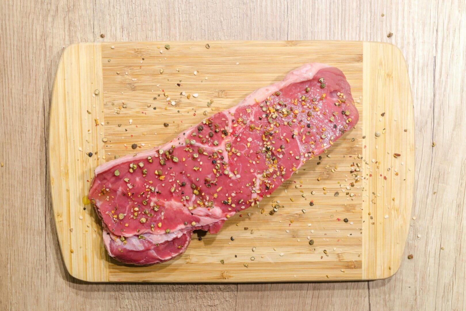 A piece of meat on top of a wooden cutting board.