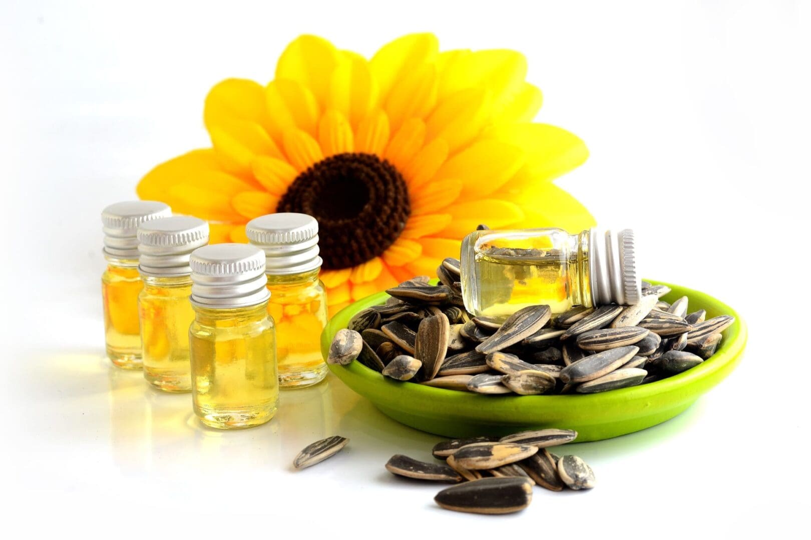 A bowl of sunflower seeds and three bottles of oil.