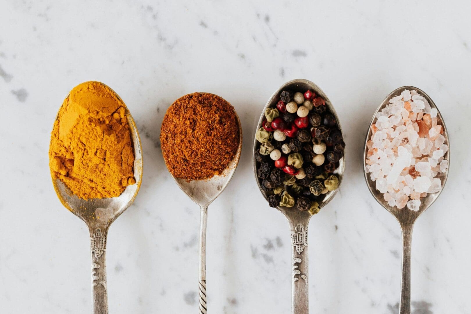 A group of spoons filled with different types of spices.