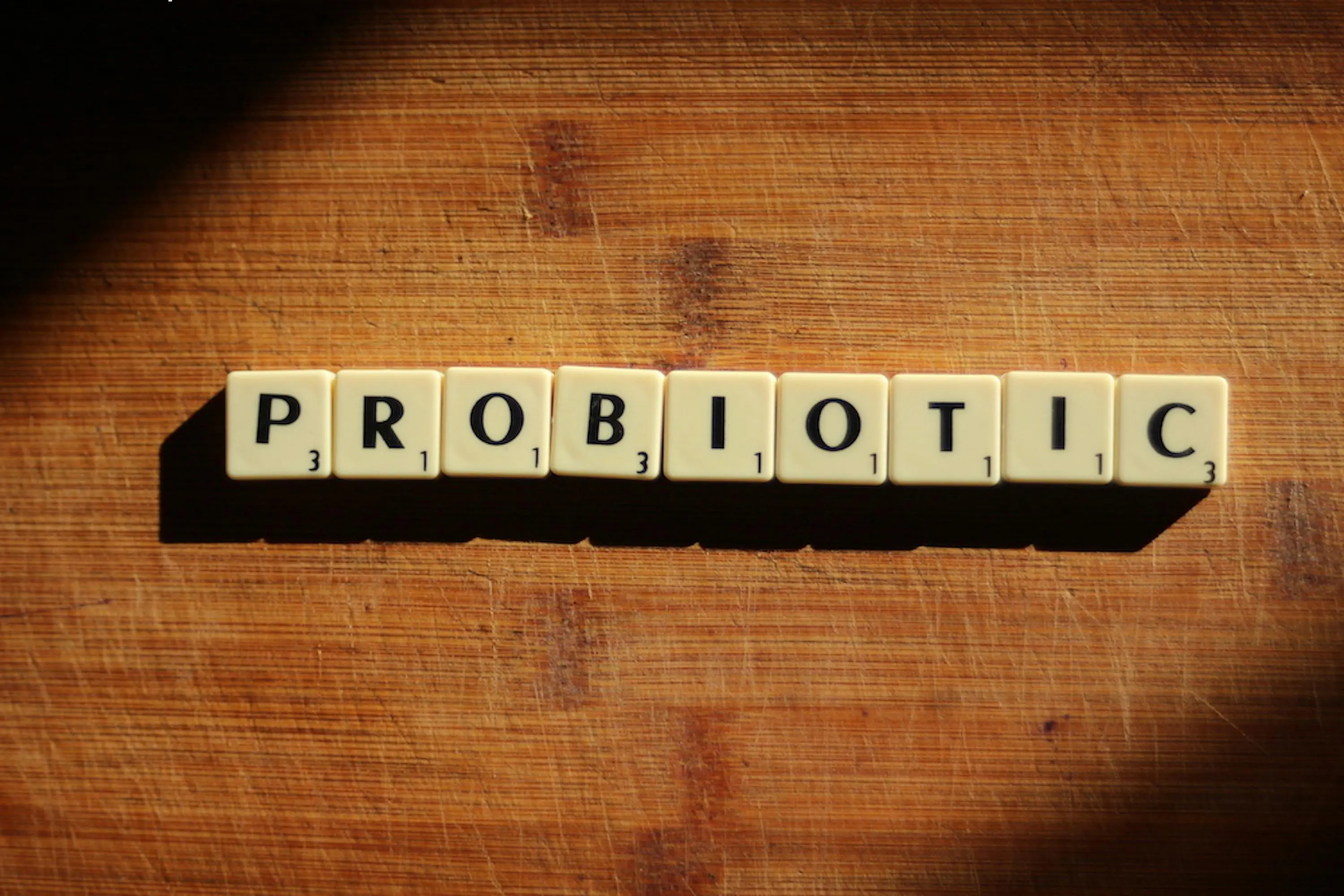 A wooden table with scrabble tiles spelling out the word probiotic.